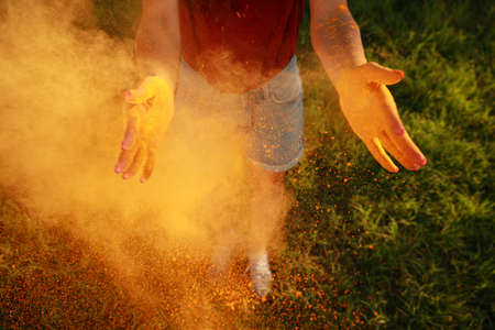 Woman with orange powder dye outdoors, closeup. Holi festival celebration