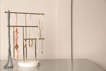 Holder with set of luxurious jewelry on gray table. Space for text