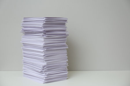 Stack of paper sheets on white table. Space for textの写真素材