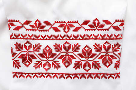 Beautiful red Ukrainian national embroidery on white fabric, top viewの写真素材