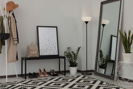 Stylish hallway room interior with bench, shoes, clothes rack and floor mirrorの写真素材