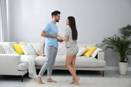 Happy couple in pajamas dancing at home
