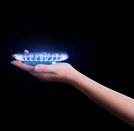 Closeup view of woman holding gas burner with blue flame on black background