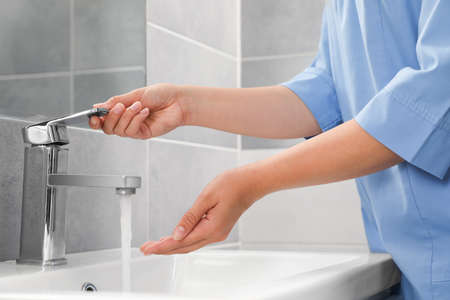 Doctor washing hands with water from tap in bathroom, closeupの写真素材