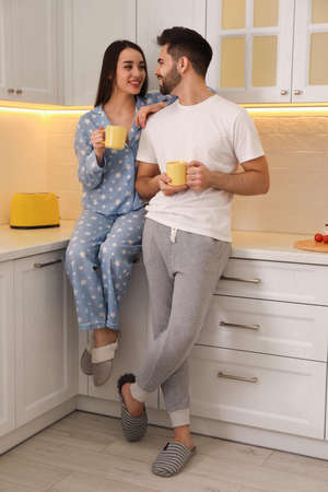 Happy couple in pajamas having breakfast at homeの写真素材