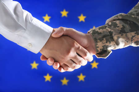 Soldier and businessman shaking hands against flag of European Union, closeupの写真素材