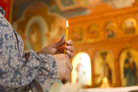 Mature woman holding candle in church, closeup. Space for textの写真素材