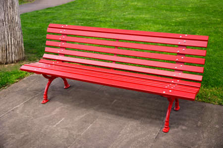 Beautiful red wooden bench near green grass in parkの写真素材