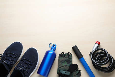 Flat lay composition with different cycling accessories on wooden background, space for text