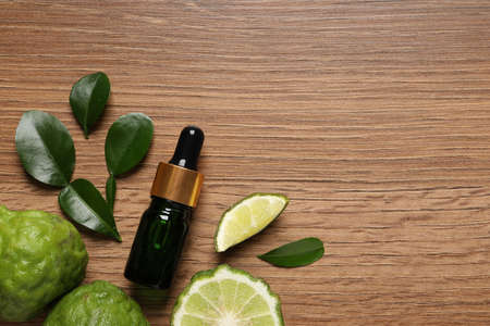 Glass bottle of bergamot essential oil and fresh fruits on wooden table, flat lay. Space for textの写真素材