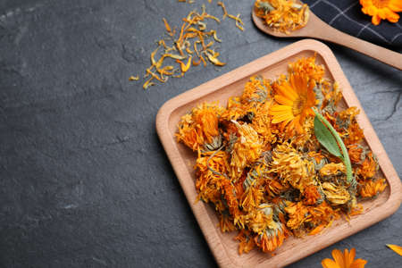 Dry and fresh calendula flowers on black table, flat lay. Space for textの写真素材