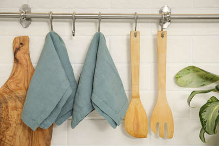 Clean towels and utensils hanging on rack in the kitchenの写真素材