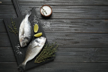 Raw dorada fish on black wooden table, flat lay. Space for textの写真素材