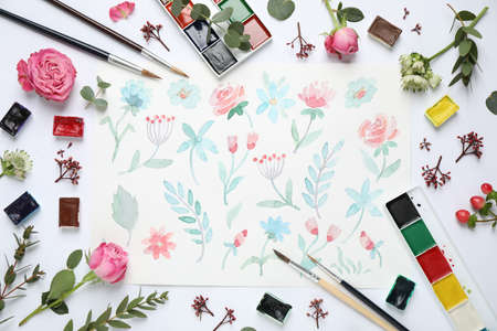 Flat lay composition with watercolor paints and floral picture on white background