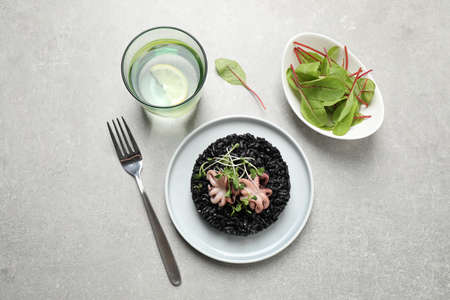 Delicious black risotto with seafood served on light gray table