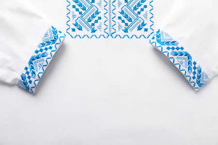 Beautiful white shirt with light blue Ukrainian national embroidery, top view. Space for textの写真素材