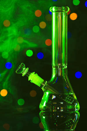 Glass bong with smoke against blurred lights, toned in green. smoking deviceの写真素材