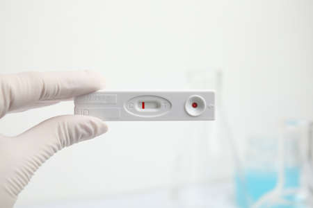 Doctor holding disposable express test for hepatitis indoors, closeup