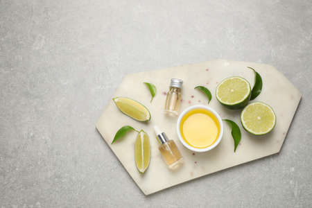Lime essential oil and cut citrus fruits on light gray table, top viewの写真素材