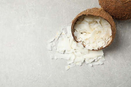 Tasty coconut chips and shell on gray table, above view. Space for text