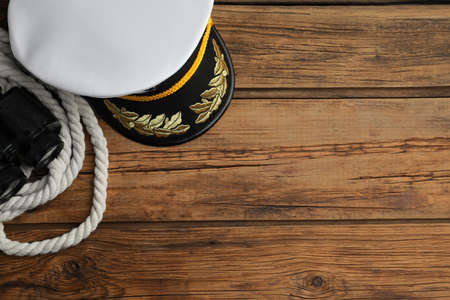 Peaked cap, rope and binoculars on wooden background, flat lay. Space for textの写真素材