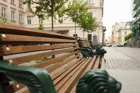 View of wooden bench with wrought legs on city streetの写真素材
