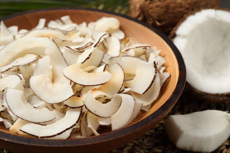 Tasty coconut chips in wooden bowl, closeup