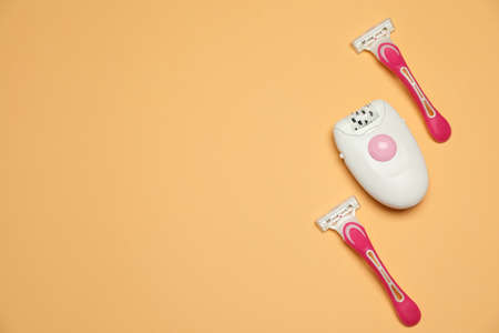 Modern epilator and razors on orange background, flat lay. Space for textの写真素材