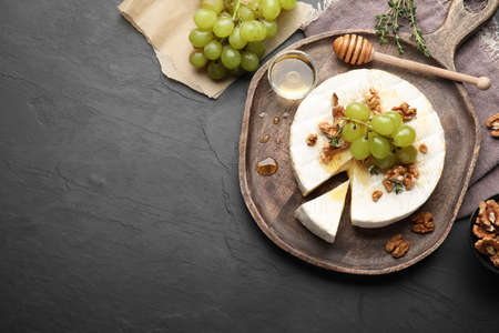 Brie cheese served with grapes, walnuts and honey on gray table, flat lay. Space for textの写真素材