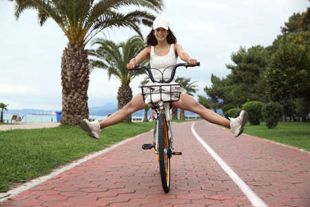 Beautiful young woman riding bicycle on lane outdoors