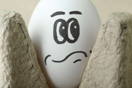 Egg with drawn thoughtful face in cardboard package, closeupの写真素材
