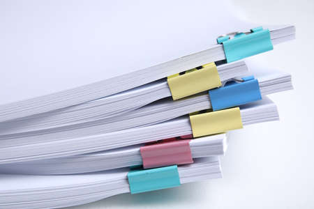 Many sheets of paper with colorful clips on white background, closeup