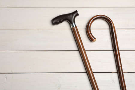Different elegant walking canes on white wooden table, flat lay. Space for text