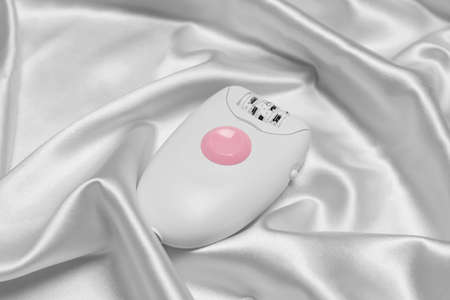 Modern epilator on white silk fabric. hair removalの写真素材