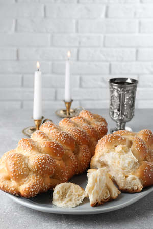 Homemade braided bread with sesame seeds, goblet and candles on gray table, closeup. Traditional Shabbat challahの写真素材