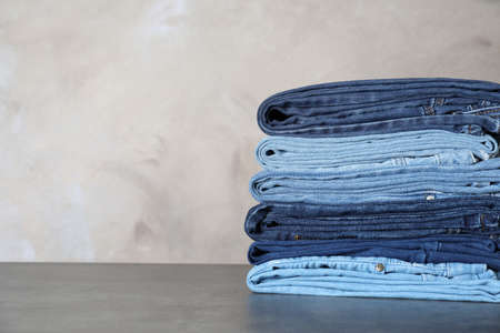 Stack of different jeans on gray table. Space for textの写真素材