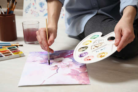 Woman painting flowers with watercolor on floor, closeupの写真素材