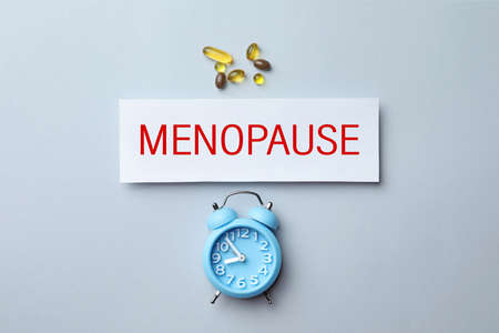 Card with word Menopause, pills and alarm clock on white background, flat layの写真素材