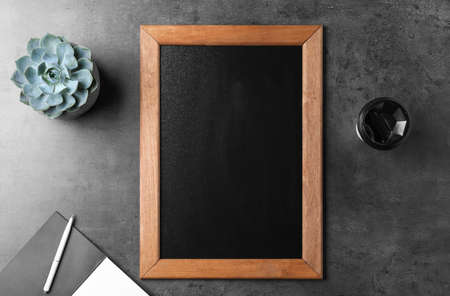Clean small chalkboard, coffee and plant on gray table, flat lay