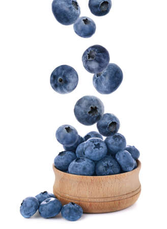 Tasty fresh ripe blueberries falling into bowl on white backgroundの写真素材