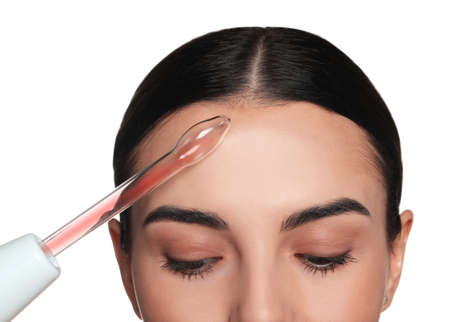 Woman using high frequency darsonval device on white background, closeup