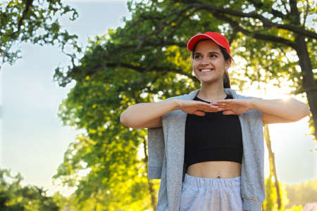 Young woman doing morning exercise in the park. Space for text