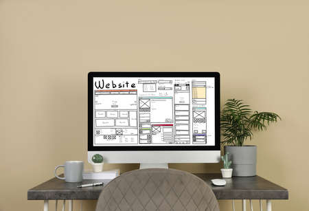 Computer with sketch of website planning and design on gray table