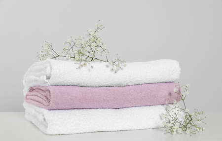 Clean soft towels with flowers on white table against light gray backgroundの写真素材