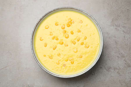 Delicious creamy corn soup on gray table, top view
