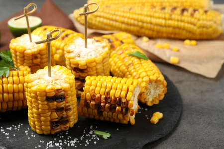 Tasty grilled corn on gray table, closeup
