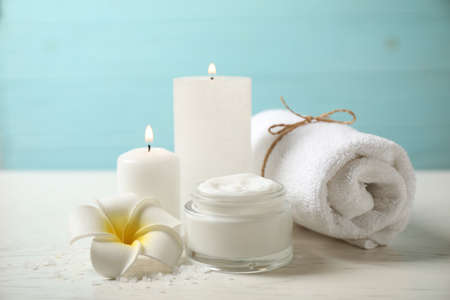 Composition with cream and burning candles on white wooden table. spa treatment