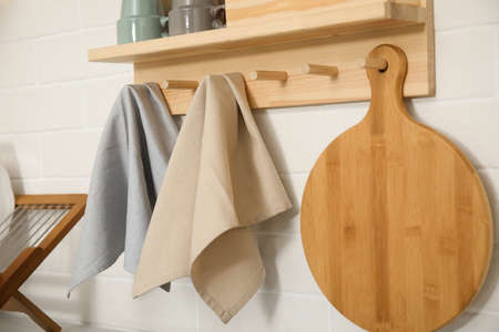 Different towels and wooden board hanging on rack in kitchenの写真素材