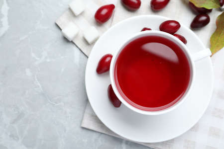 Cup of fresh dogwood tea and berries on light gray table, flat lay. Space for textの写真素材