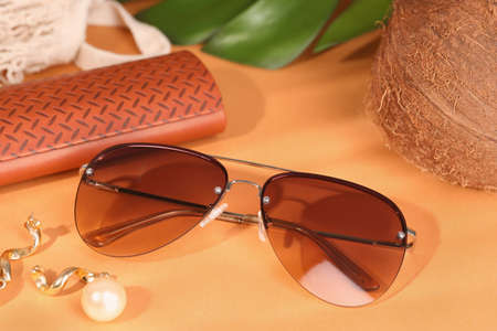 Stylish sunglasses and brown leather case on pale orange backgroundの写真素材